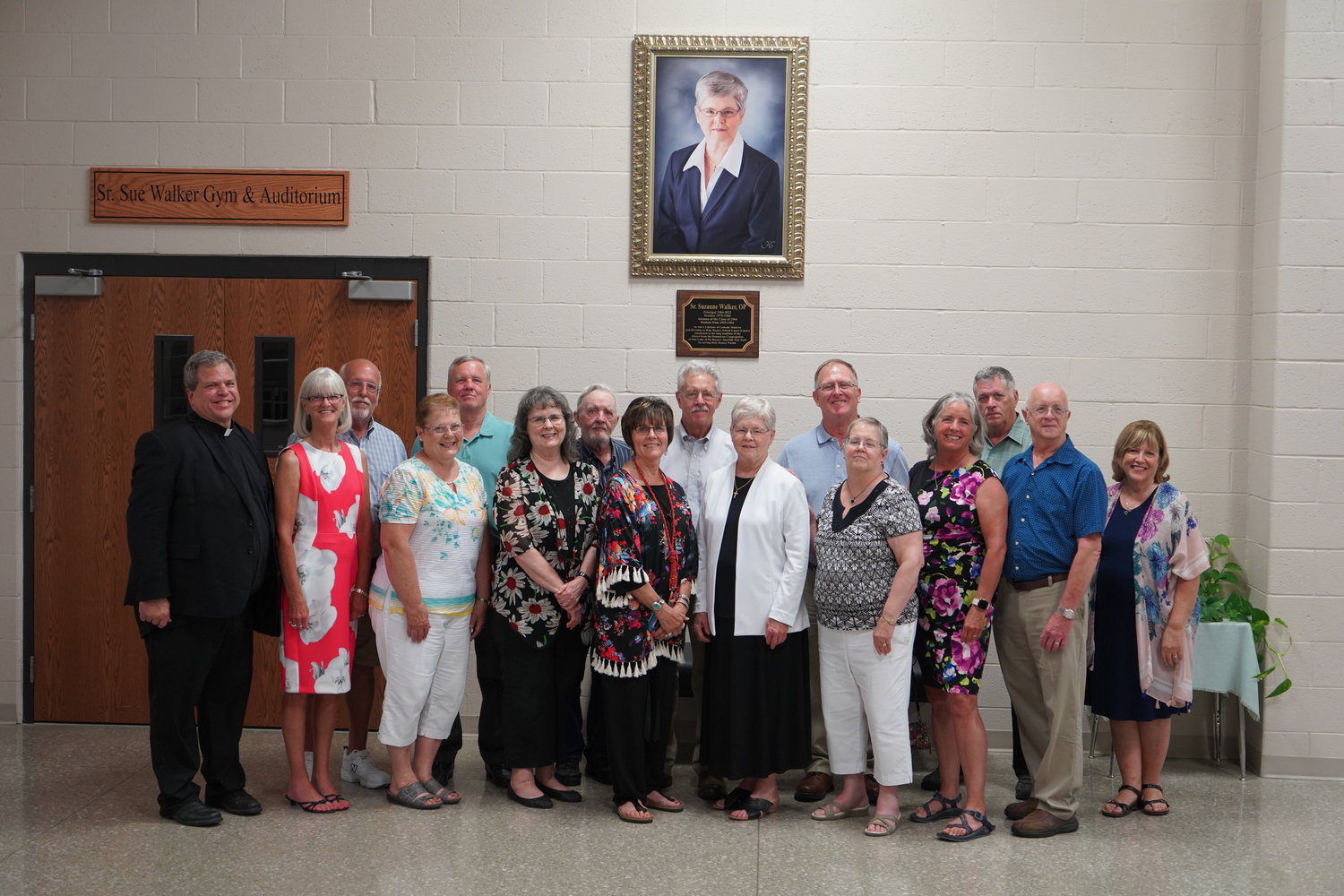Dominican Sister Suzanne Walker, members of her family and Father Gregory Oligschlaeger gather for a photo outside the newly-named Sister Sue Walker Gym and Auditorium in Holy Rosary School in Monroe City.